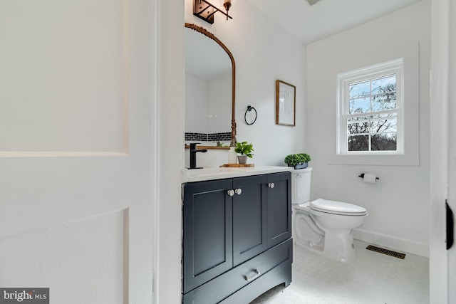 half bathroom with vanity, baseboards, visible vents, tile patterned floors, and toilet