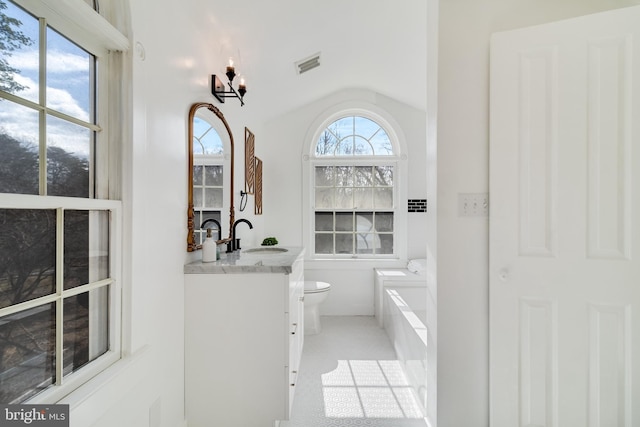 full bathroom with visible vents, toilet, a tub, vanity, and vaulted ceiling