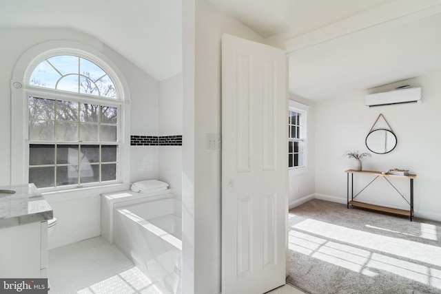 bathroom with baseboards, a washtub, an AC wall unit, vaulted ceiling, and vanity