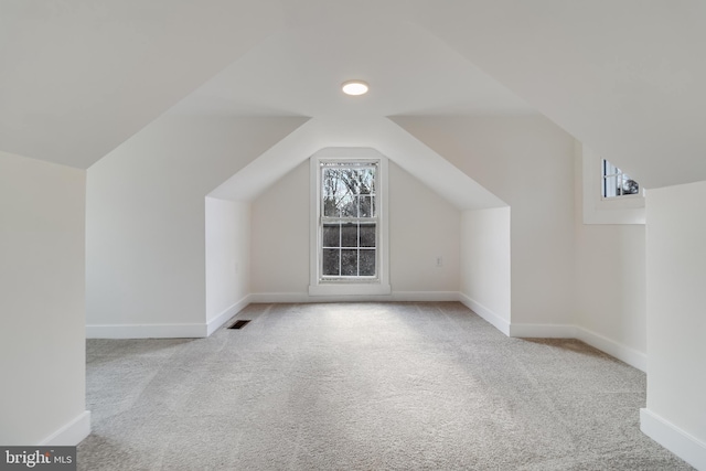 additional living space featuring lofted ceiling, baseboards, carpet, and a healthy amount of sunlight