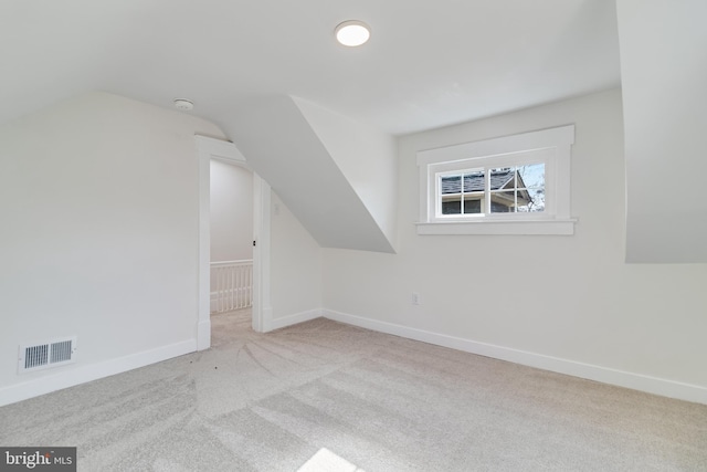 additional living space featuring vaulted ceiling, carpet flooring, baseboards, and visible vents