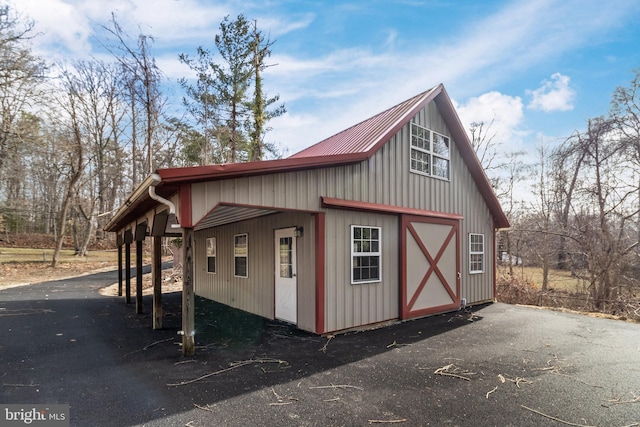 view of side of home featuring an outbuilding, metal roof, and aphalt driveway