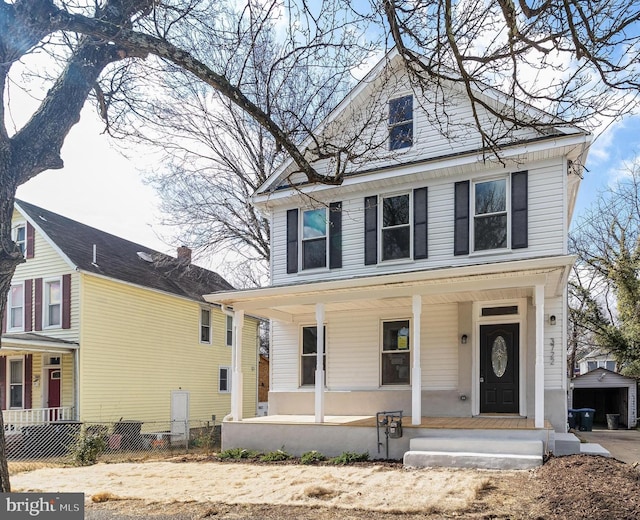 american foursquare style home featuring covered porch and fence