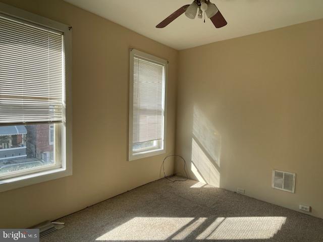 empty room featuring ceiling fan and carpet