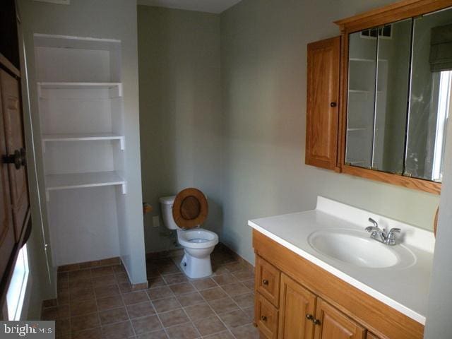 bathroom featuring toilet, tile patterned flooring, and vanity