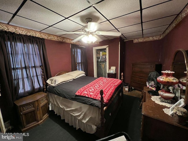 carpeted bedroom with a paneled ceiling and ceiling fan