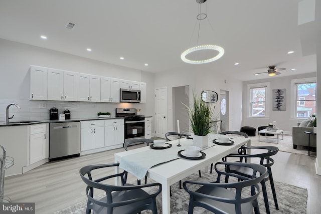 kitchen featuring dark countertops, open floor plan, stainless steel appliances, pendant lighting, and a sink