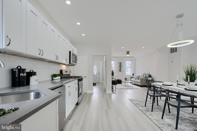 kitchen with decorative light fixtures, stainless steel appliances, visible vents, open floor plan, and white cabinets