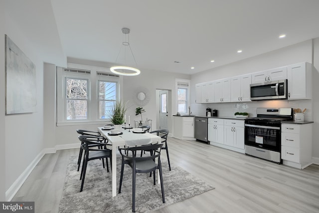 dining area with light wood-style floors, recessed lighting, and baseboards