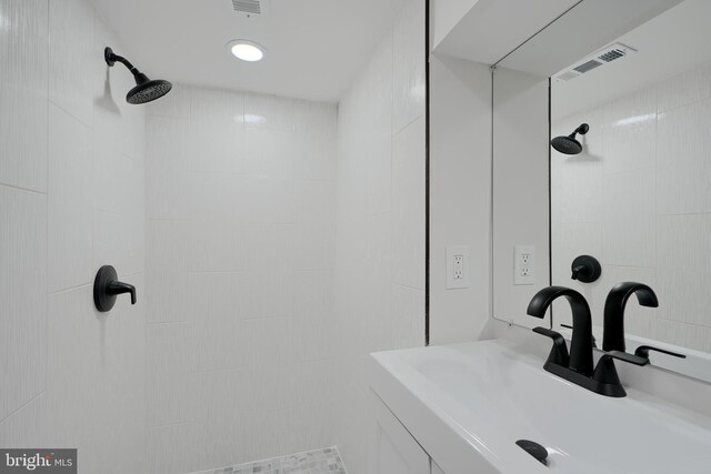 bathroom with visible vents, a sink, and tiled shower