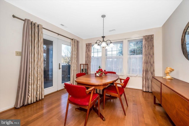 dining space featuring an inviting chandelier, hardwood / wood-style flooring, and french doors