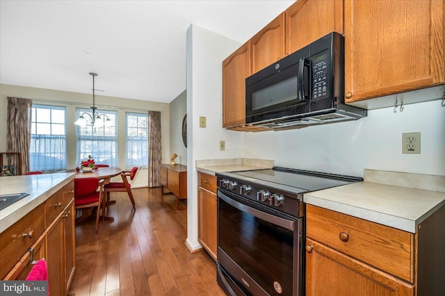 kitchen featuring electric range, lofted ceiling, hanging light fixtures, dark hardwood / wood-style flooring, and an inviting chandelier