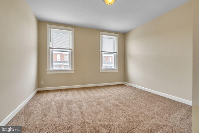 empty room featuring a healthy amount of sunlight, baseboards, and carpet flooring