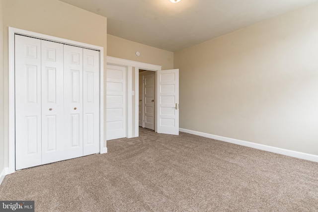 unfurnished bedroom with carpet, a closet, and baseboards