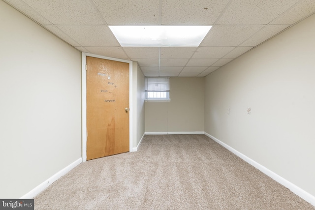 below grade area featuring a paneled ceiling, carpet, and baseboards