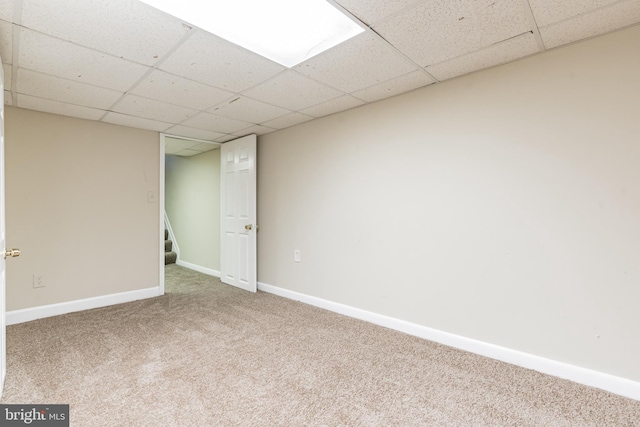 finished below grade area with a drop ceiling, stairway, carpet, and baseboards