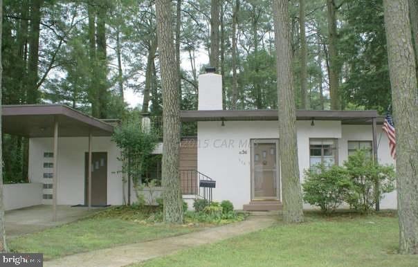 view of front of home featuring entry steps, a chimney, a front lawn, and stucco siding