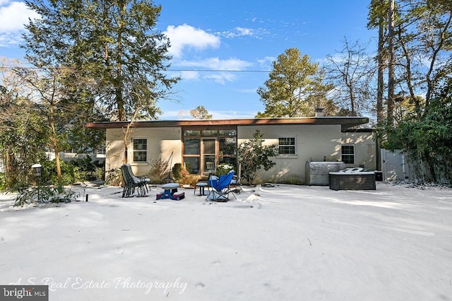 snow covered property featuring an outdoor fire pit and stucco siding