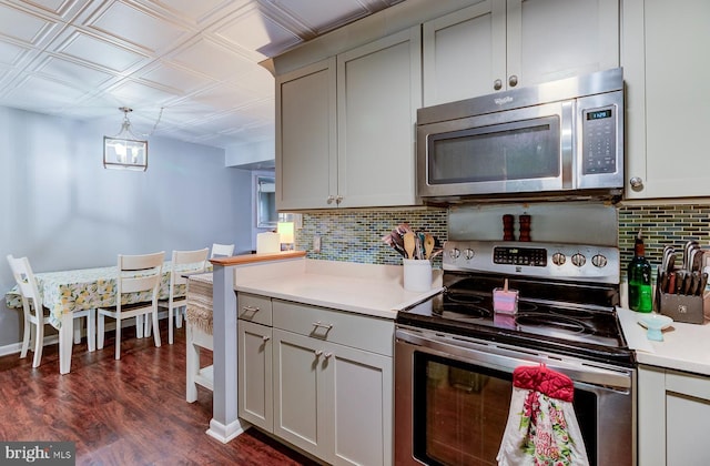 kitchen with dark wood-type flooring, appliances with stainless steel finishes, light countertops, and backsplash