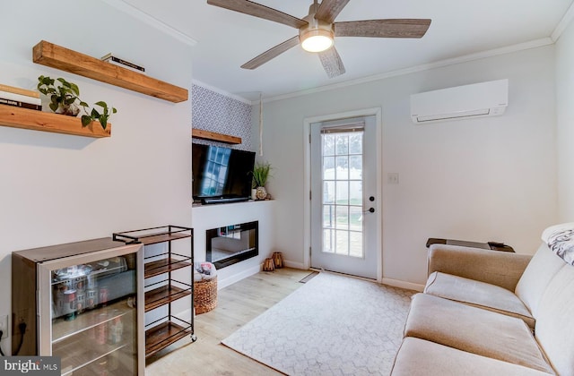 living area featuring a glass covered fireplace, an AC wall unit, crown molding, and light wood finished floors