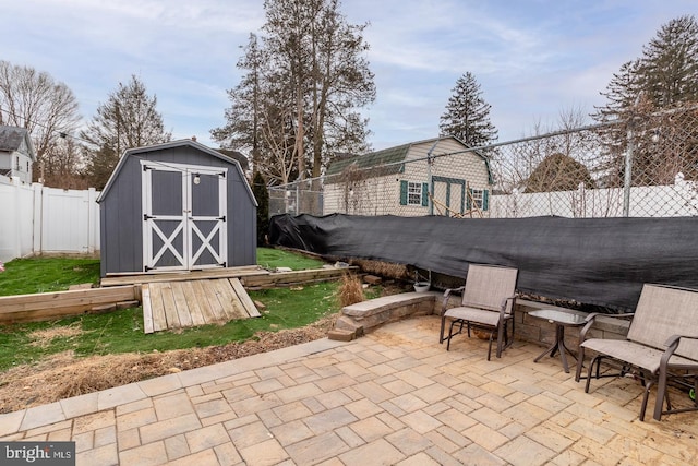 view of patio featuring an outbuilding, a fenced backyard, and a storage shed