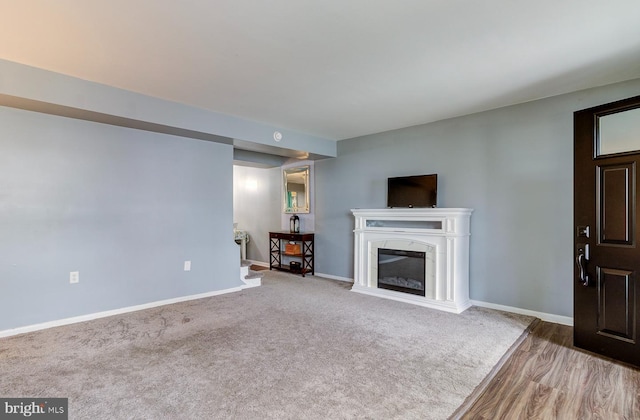 unfurnished living room with carpet, a fireplace, and baseboards