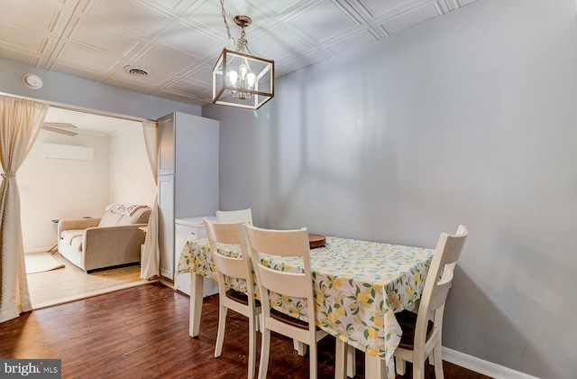 dining area featuring visible vents, baseboards, a wall unit AC, dark wood-style floors, and an ornate ceiling