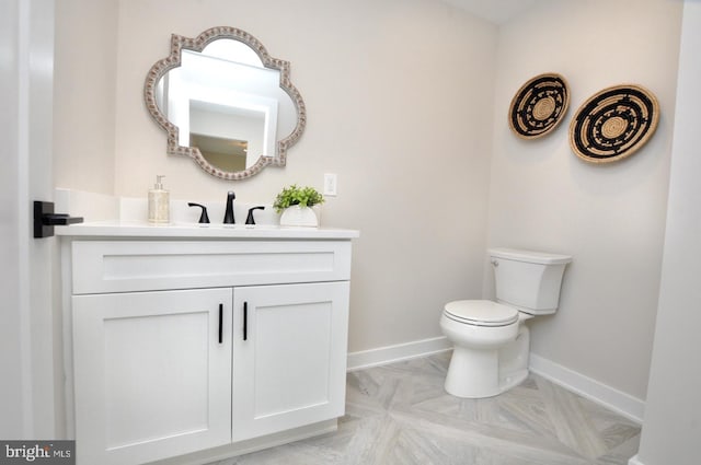 bathroom with toilet, baseboards, and vanity