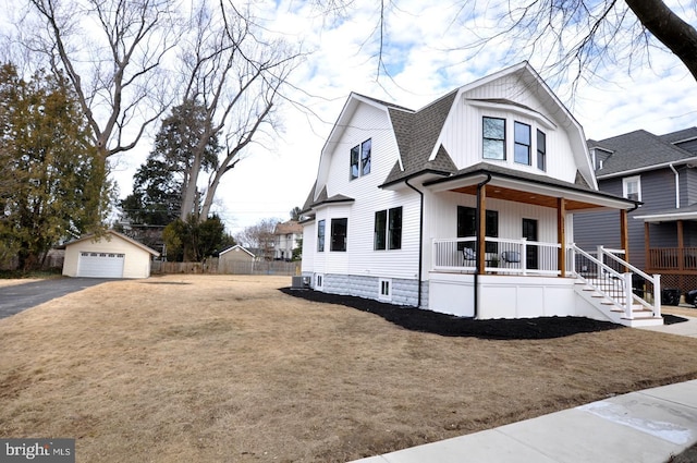 view of front of property featuring a porch, a shingled roof, a gambrel roof, an outdoor structure, and a front lawn