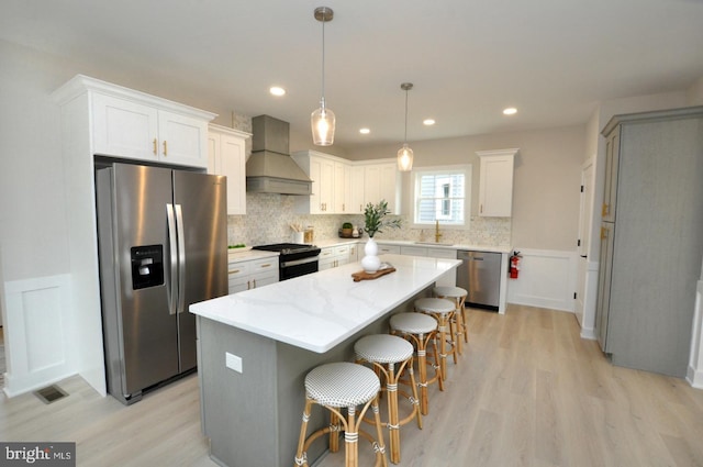 kitchen with a center island, a breakfast bar area, stainless steel appliances, a sink, and premium range hood