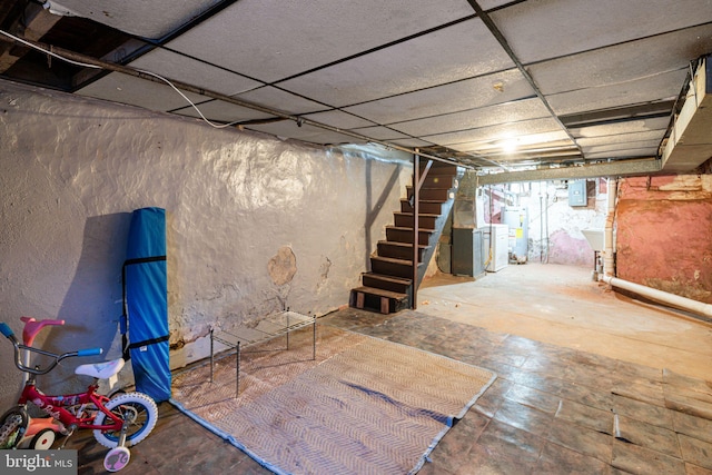 basement with stairs, electric panel, a drop ceiling, and gas water heater