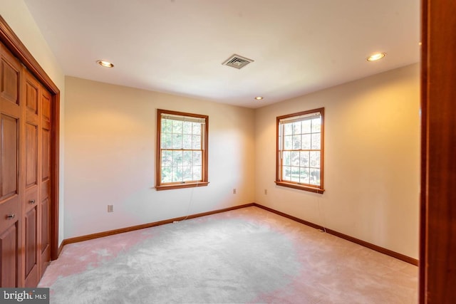 interior space featuring multiple windows, a closet, and light colored carpet