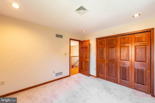 unfurnished bedroom with light carpet and a closet