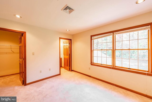 unfurnished bedroom featuring a closet, a spacious closet, and light colored carpet