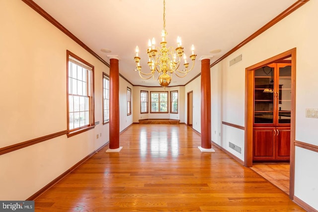 unfurnished dining area featuring light hardwood / wood-style floors, ornate columns, and crown molding