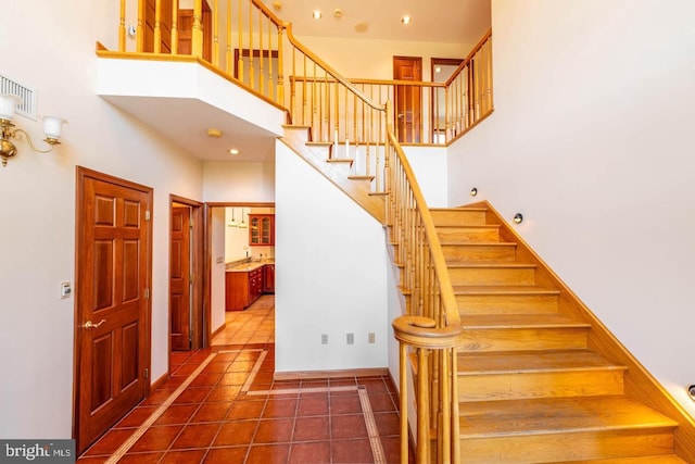 stairs featuring a high ceiling and tile patterned flooring