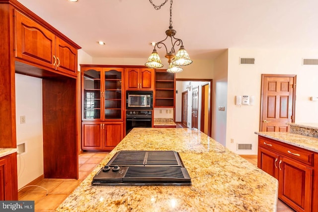 kitchen with light tile patterned floors, black appliances, light stone counters, and pendant lighting