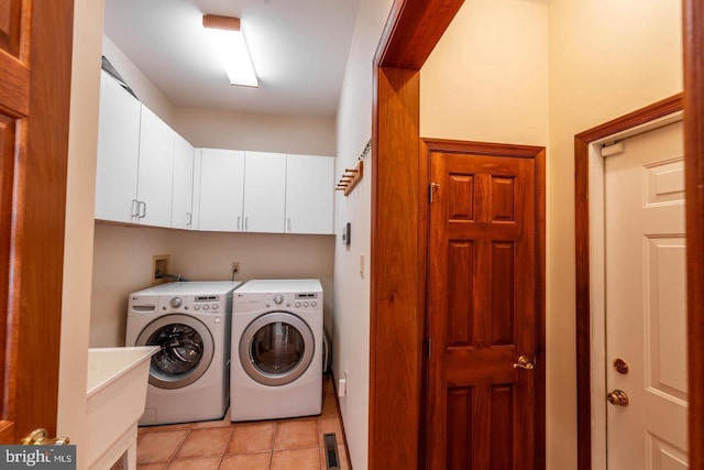 laundry room with cabinets, light tile patterned floors, and washer and clothes dryer