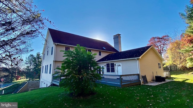 rear view of house featuring central AC unit, a yard, and a wooden deck