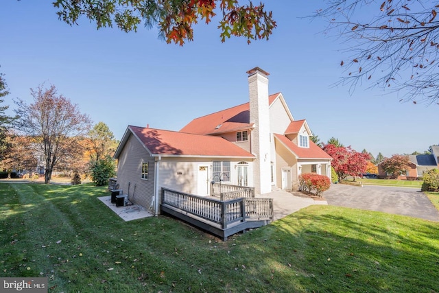 rear view of property with a lawn, a wooden deck, and central AC unit