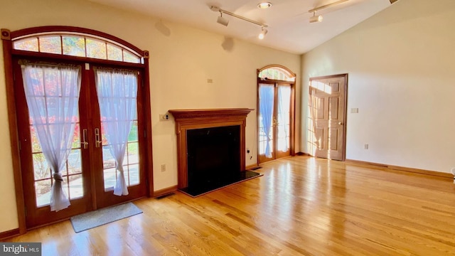 unfurnished living room featuring light wood-type flooring, french doors, and a healthy amount of sunlight