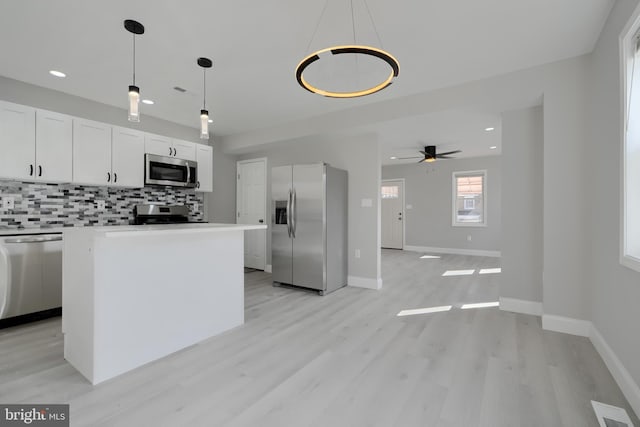 kitchen featuring a center island, light countertops, hanging light fixtures, appliances with stainless steel finishes, and white cabinets