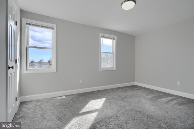 carpeted empty room featuring baseboards and visible vents