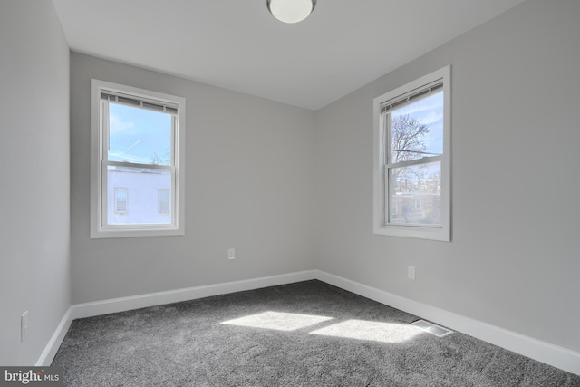 empty room with carpet flooring, visible vents, and baseboards