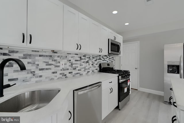 kitchen featuring a sink, white cabinetry, light countertops, appliances with stainless steel finishes, and backsplash