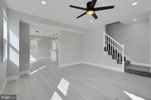 unfurnished living room with ceiling fan, recessed lighting, baseboards, light wood-style floors, and stairway