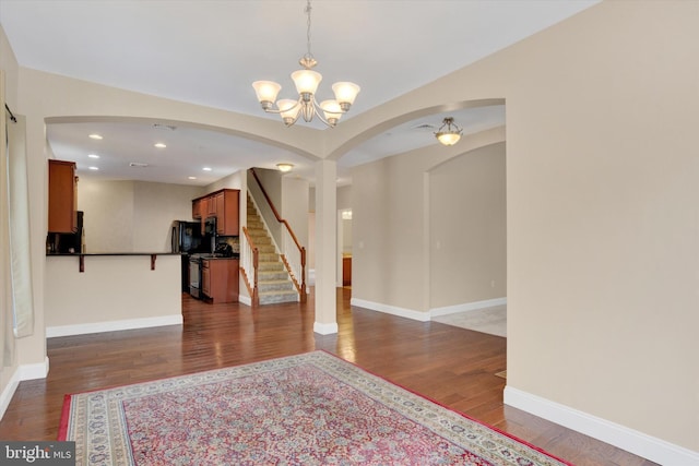 spare room with dark wood-type flooring and a chandelier