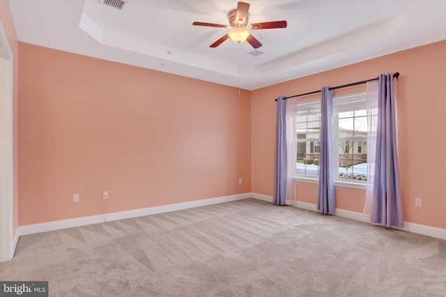 unfurnished room with light carpet, a tray ceiling, and ceiling fan