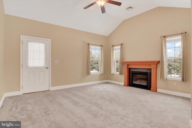 unfurnished living room featuring vaulted ceiling, a healthy amount of sunlight, and light colored carpet