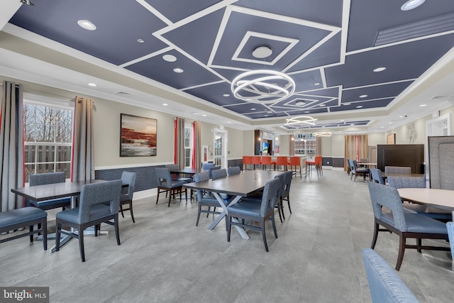 dining area featuring crown molding, a raised ceiling, and a notable chandelier